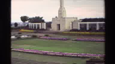 New Zealand (1981): Monument Surrounded By Flowers Is Followed By People Standing