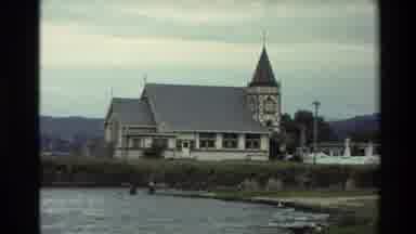 New Zealand (1981): People Standing By White Church Building Next To Shore On