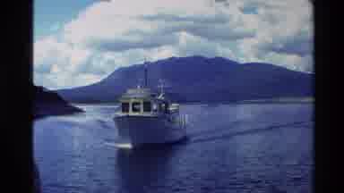 New Zealand (1981): Boat Moving Towards Screen In Water Area With Steep Rocky