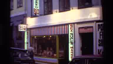 Denmark (1982): Storefront Labeled Sex Supermarket With Cars Parked Roadside Along