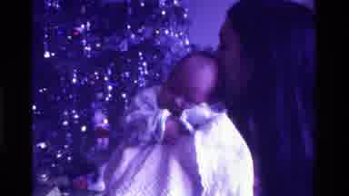 California USA (1975): A Woman Holds An Infant In Front Of A Christmas Tree