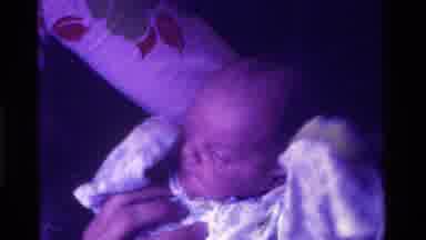 California USA (1975): Newborn Smiles At Parents In Home While Wrapped In Swaddle