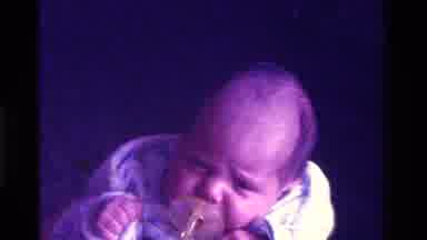 California USA (1975): Baby Sucking On Pacifier While An Adult Comforts Him In