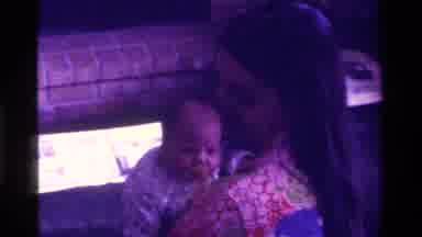 California USA (1975): A Mother With Dark Hair Holds Her Infant Child Followed By