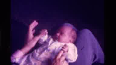 California USA (1975): Baby Playing With Mothers Hands As She Falls Asleep