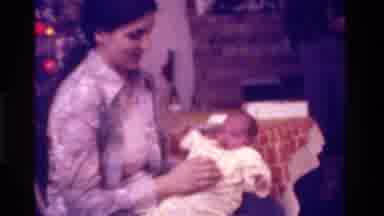 California USA (1975): Mother Holding Baby In A Rocking Chair While Baby Moves
