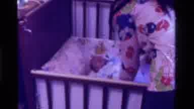 California USA (1975): Woman Lays Crying Baby To Bed On It's Back In A Crib
