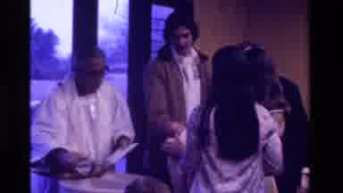 California USA (1975): Couple At Priest Who Is Giving Communion To Their Baby