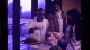 California USA (1975): Religious Figure In White Robes Pours Water On Infants