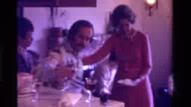 California USA (1975): Woman Serves Cake To Guests At Small Home Social Gathering