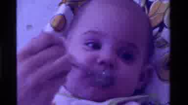 California USA (1975): Infant Being Fed Solid Food With Silver Spoon While Laying