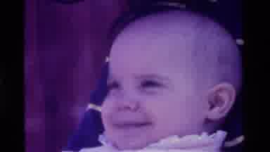California USA (1975): Smiling Baby Looks Upward To The Right Before Glancing Over