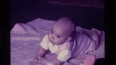 California USA (1975): A Baby Lying On A Blanket Moving Its Legs And Arms