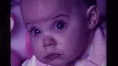 California USA (1975): Baby Looks Intently At The Camera Then Twitches Mouth And