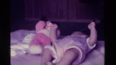 California USA (1975): Little Baby Wiggles Legs In Bed And Plays With Mickey Mouse