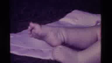 California USA (1975): Baby Lying On His White Sheets And Wiggling His Legs