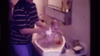 California USA (1975): Mother Bathing Baby In Plastic Tub On Top Of The Bathroom