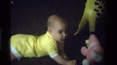 California USA (1975): Infant Looks At Pink Toy Then Looks At Camera Before
