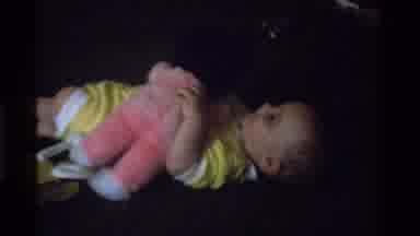 California USA (1975): Cute Baby In Yellow Dress Playing With Doll Infant Love For