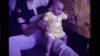 California USA (1975): A Small And Cute Baby In Yellow Playing With His Mother