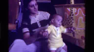 California USA (1975): Woman Wearing Black White Shirt Holds Baby Wearing Yellow