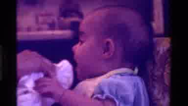 California USA-1975: Playful Baby Resisting Face Cleaning With Cloth