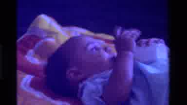 California USA (1975): Baby Lying On Its Back With Milk Bottle In Its Mouth