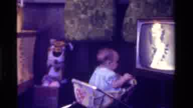 California USA (1975): Baby Girl Walking Around In Her Walker In Living Room