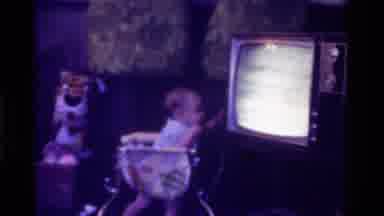 California USA (1975): Baby In A Crib Knocking On An Old Television Emitting