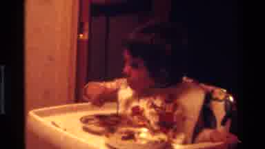 California USA (1977): Child Feeding Himself Sitting At Highchair