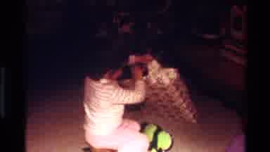 California USA (1977): Child Opening Christmas Present Taking Off Wrapping Paper