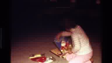California USA (1977): Little Girl In White Striped Shirt On Indoor Carpet Picking