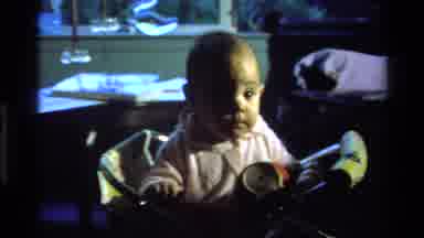California USA (1977): The Cute Little Baby Stares At A Cup She Is Holding While