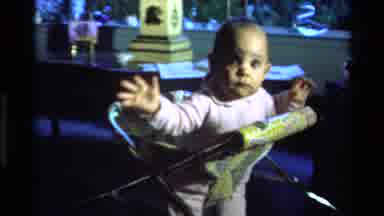 California USA (1977): Baby In Pink Shirt Bouncing And Turning In Yellow Chair In