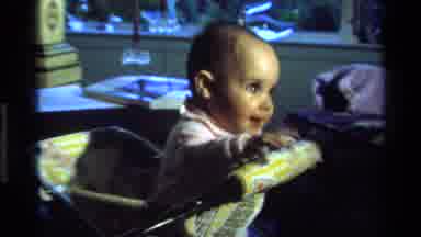 California USA (1977): Baby Bouncing Up And Down In Special Chair With His Hand In