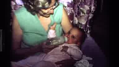 California USA (1977): Loving Mother Cuddling Baby While Feeding With A Bottle