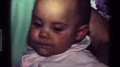 California USA (1977): A Mother Is Feeding Her Child And The Child Is Blinking