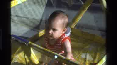 California USA (1977): Toddler In Red And White Striped Onesie In Yellow Playpen