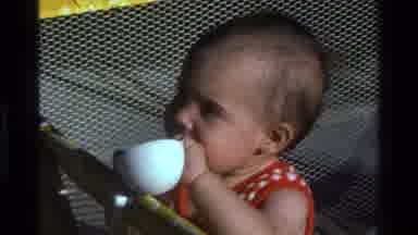 California USA (1977): A Baby Inside A Crib Watching And Biting A Mug