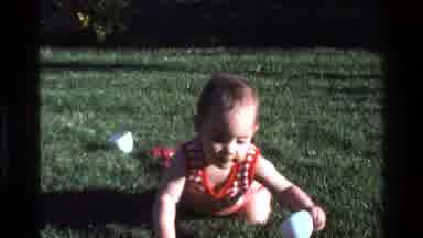 California USA (1977): Adorable Baby Crawls Across The Backyard While Parents Film
