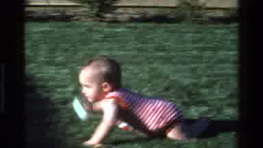 California USA (1977): A Baby In Horizontal Red Stripe Clothe Playing With White