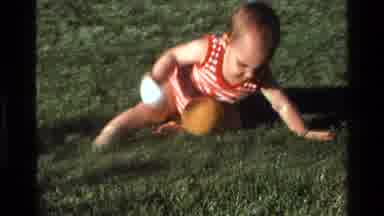 California USA (1977): A Small Kid Is Playing With Two Balls In The Meadow