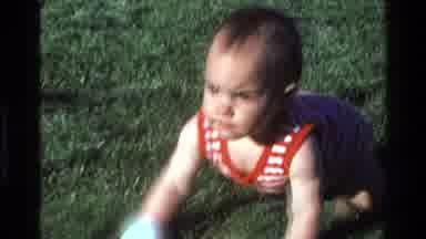 California USA (1977): Woman Lays On Grass As Young Child Crawls Toward Her With