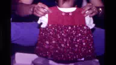 California USA (1977): A Little Baby Receiving A New Dress From Her Mom