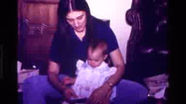 California USA (1977): A Woman Holding A Baby Who Is Opening A Wrapped Present