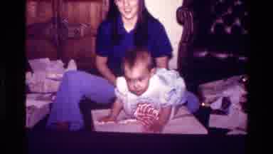California USA (1977): Woman Sitting On The Floor Playing With A Little Baby Who