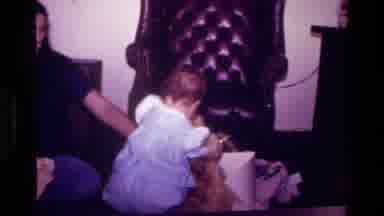 California USA (1977): Baby In A Dress With Parent Waving Oversized Teddy Bear