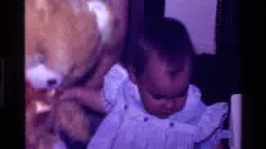 California USA (1977): A Baby Cuddles A Gold Teddy With A Big Red Bow