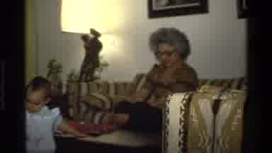 California USA (1977): A Family Watching Baby Opening Christmas Gifts In The
