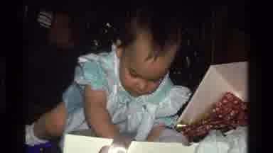 CALIFORNIA USA-1977: Baby Wearing White And Blue Clothes Opens Gift From Box